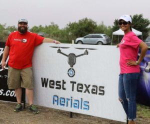 West Texas Aerials poses for photo in fron of sponsorship sign at the annual Peace Love and Mud Volleyball fundraiser.